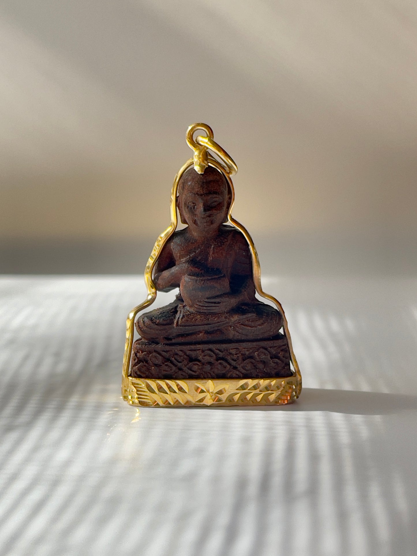 Wooden Khmer style Buddha in a gold plated mounting.